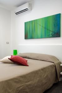uma cama com uma almofada vermelha e uma pintura na parede em Sea Salt em Porto Cesareo