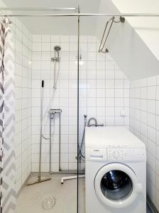 a washing machine in a bathroom with a shower at Kåseberga Byhus in Ystad