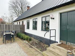 a white house with a green door and a table at Kåseberga Byhus in Ystad