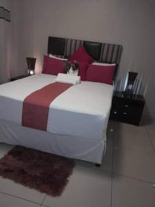 a bedroom with a large bed with red pillows at Mokoka Rest Camp in Nata