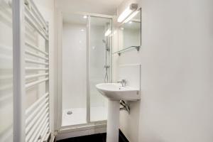 a white bathroom with a sink and a shower at Studio 2 pers - Wifi limite Vincennes & métro (E3) in Montreuil
