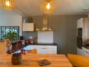 - une cuisine avec une table en bois et deux lumières dans l'établissement Cocon de douceur à deux pas de la gare, à Montauban-de-Bretagne