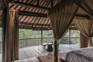 Un dormitorio con una cama y un balcón con una mesa. en Jungle House Estate, en Gianyar