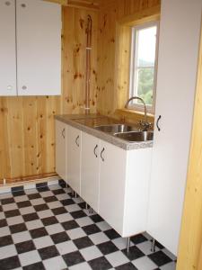 a kitchen with a sink and a checkered floor at Markusfolks Gård in Torsby