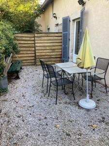 einen Tisch und Stühle mit gelbem Regenschirm in der Unterkunft appartement terrasseLouhans centre in Louhans