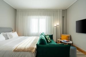 a bedroom with a bed and two chairs and a television at Syntagma Bliss: Athens Hub in Athens