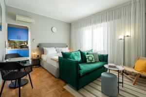 a bedroom with a bed and a green couch at Syntagma Bliss: Athens Hub in Athens
