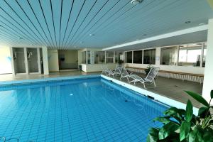 a large swimming pool with chairs in a building at Apartment "Schlupfwinkel" im Haus Feldbergblick, Lenzkirch, Innenpool, Sauna in Lenzkirch