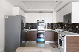 a kitchen with white cabinets and a washer and dryer at 2BHK Gem at Jewelz by Danube in Dubai
