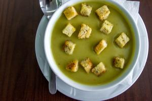 a bowl of soup with croutons in it on a plate at Hotel Riga in Arad