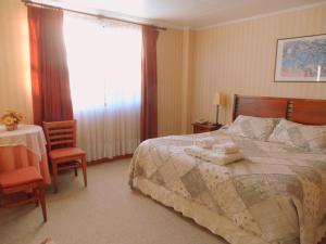a bedroom with a bed, chair, desk and lamp at Lady Florence Dixie in Puerto Natales