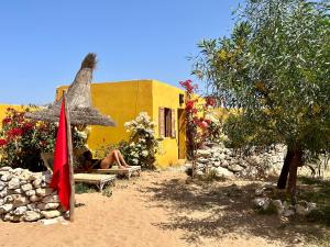 een man op een bank naast een geel gebouw bij Éco-Ranch Salomé in Sidi Kaouki