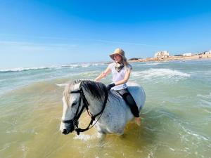 een vrouw op een paard in de oceaan bij Éco-Ranch Salomé in Sidi Kaouki