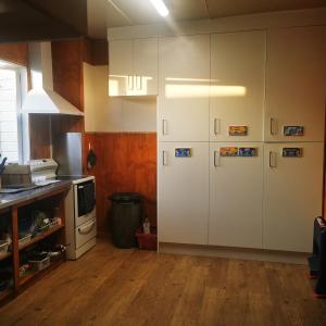 uma cozinha com armários brancos e piso em madeira em Bluewater Lodge em Napier