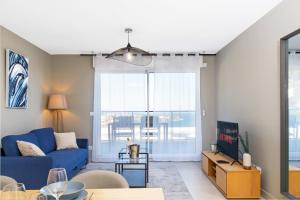 een woonkamer met een blauwe bank en een groot raam bij Luxury apartment - Sea View - Private parking in Beausoleil