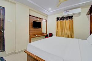 sypialnia z białym łóżkiem i telewizorem w obiekcie Super OYO Flagship 80823 Hotel Sitara Grand w mieście Visakhapatnam