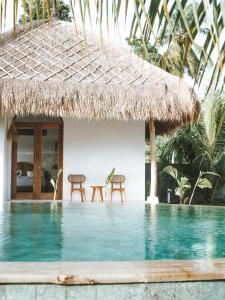 a resort with a swimming pool and two chairs at Luana Lombok in Selong Belanak