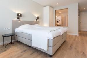 Schlafzimmer mit einem großen weißen Bett und Holzboden in der Unterkunft Zeayou Zeeland - Studio's Zuidstraat 1 in Domburg