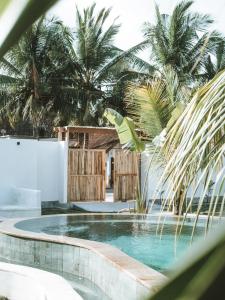 una piscina con palmeras en el fondo en Luana Lombok en Selong Belanak