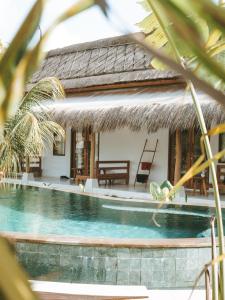 a villa with a swimming pool in front of a house at Luana Lombok in Selong Belanak