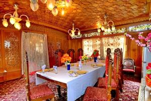 une salle à manger avec une table et des chaises blanches dans l'établissement Heritage Amina Group of Houseboats, à Srinagar