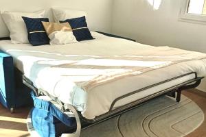 - un lit sans lit avec des draps et des oreillers bleus et blancs dans l'établissement Studio proche paris avec jardin, à Saint-Gratien