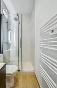 La salle de bains blanche est pourvue d'une douche et de toilettes. dans l'établissement Studio proche paris avec jardin, à Saint-Gratien