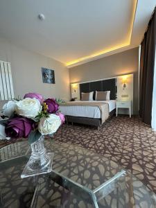 The Conforium Hotel Van في فان: غرفة في الفندق بها سرير و مزهرية من الزهور