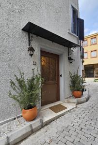 eine Tür zu einem Gebäude mit zwei Topfpflanzen davor in der Unterkunft Origin Suites Urla in Urla