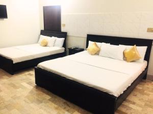 sypialnia z 2 łóżkami z białymi i żółtymi poduszkami w obiekcie Second Home Guest House Near Agha Khan Hospital , Airport, Ghulshan e Jamal Karachi w mieście Karaczi