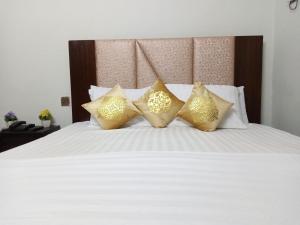 a white bed with gold pillows on it at Second Home Guest House Near Agha, Khan Airport in Karachi