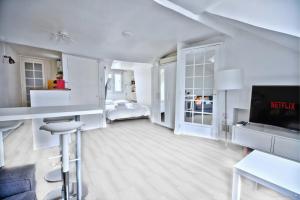 een witte woonkamer met een bed en een televisie bij Promo! near The Pantheon - Latin Quarter! in Parijs