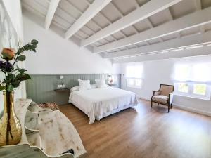 1 dormitorio con 1 cama blanca y 1 silla en Agroturismo Santa Mariana, en Alaior