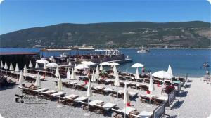 a bunch of chairs and umbrellas on a beach at Apartmani Milena in Herceg-Novi