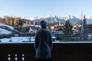 uma mulher de pé numa varanda com vista para as montanhas em Hotel Seespitz Seefeld Superior em Seefeld no Tirol