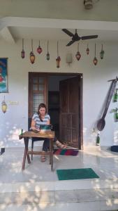 una mujer sentada en una mesa en una habitación en ABRU'S Holidays Foreign travelers, en Alleppey