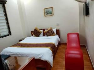 ein Schlafzimmer mit einem Bett und einem roten Stuhl in der Unterkunft Nhà Nghỉ Như Ý Ngã 6 in Pho Mới