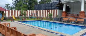 a swimming pool with chairs and a playground at Villa London Puncak in Sampal 2