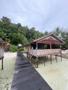 a wooden walkway leading to a hut on a beach at Junior Homestay in Kri