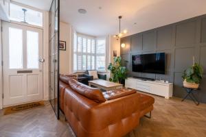 a living room with a leather couch and a television at Luxury 3 Bed House in Central Wimbledon Sleeps 7 in London