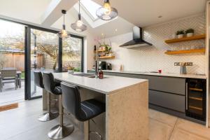a kitchen with a large island with black bar stools at Luxury 3 Bed House in Central Wimbledon Sleeps 7 in London