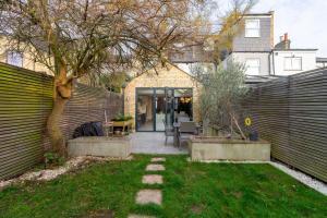 a backyard with a fence and a tree at Luxury 3 Bed House in Central Wimbledon Sleeps 7 in London