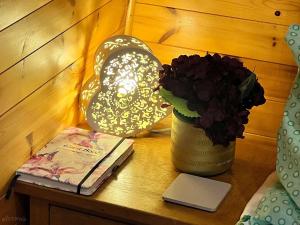 a table with a lamp and a book and a vase of flowers at Beautiful Twin Glamping Pod in Salisbury in Salisbury