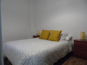 a bedroom with a bed with two yellow pillows at Casa Sardiguera in Montecorto