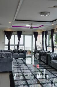 ein Wohnzimmer mit Sofas und Fenstern in der Unterkunft Villa London Puncak in Sampal 2