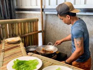 człowiek gotujący jedzenie w woku na kuchence w obiekcie Backpacker Hostel and Jungle Trekking w mieście Banlung