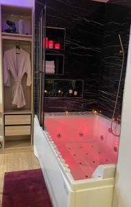 a bathroom with a red tub with a black wall at Relax Room proche PARIS Porte de Versailles in Malakoff +14 photos