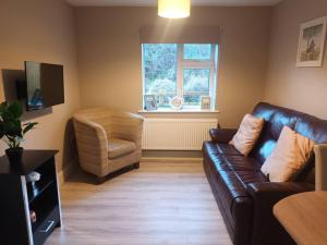 a living room with a leather couch and a chair at Beautiful House in Killarney county kerry in Coolcorcoran Bridge