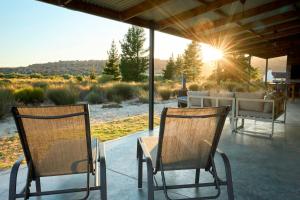 2 Stühle und ein Tisch auf einer Terrasse mit Blick auf den Sonnenuntergang in der Unterkunft Alpha Excelsior Guest Farm in Cederberg