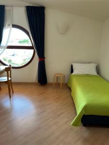 a bedroom with a green bed and a large window at Nauthotel in Grado